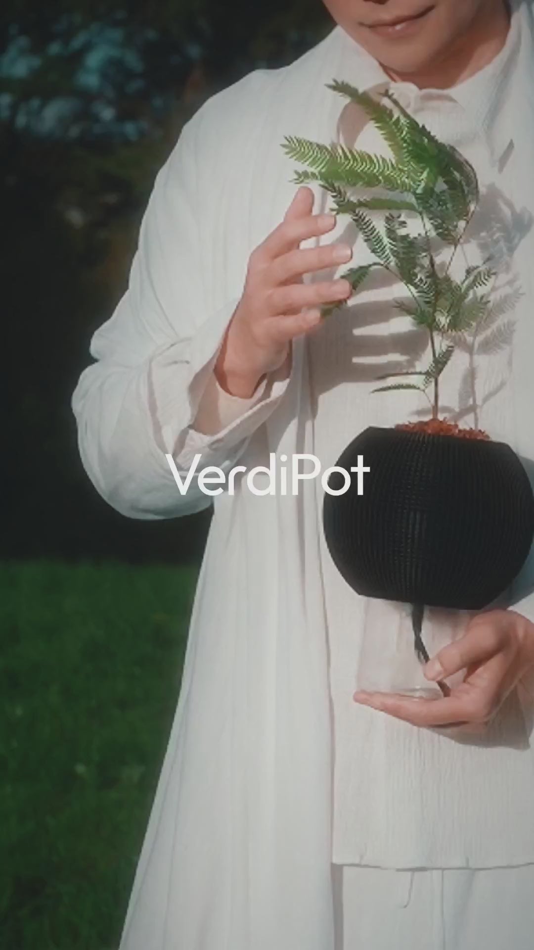 Person holding a black planter and leafy plant, with the VerdiPot name overlaid.